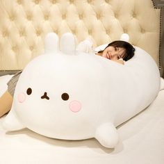 a woman laying on top of a bed with a large stuffed animal in the shape of a whale