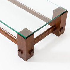 a glass and wood coffee table sitting on top of a white floor