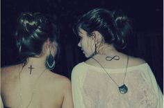 two girls with cross tattoos on their back neck and shoulders, both looking at each other