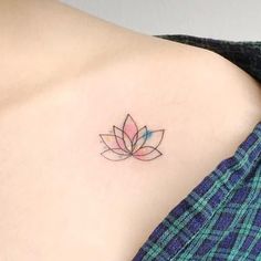 a woman's shoulder with a small tattoo of a flower on the left side