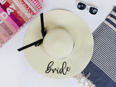 a white hat and sunglasses on top of a table with the word bride written on it