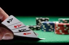 a person is playing cards on a green table with poker chips in the foreground