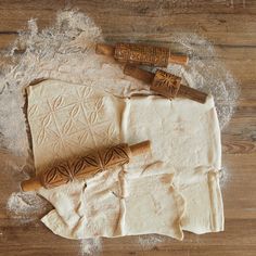 two rolling doughs on top of a wooden table next to an unwrapped rolling pin