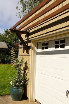 a large potted plant sitting in front of a garage door on the side of a house