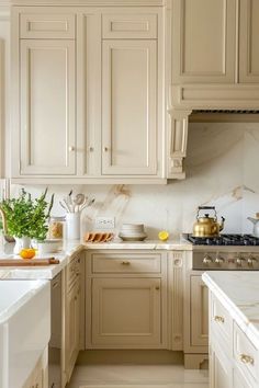 a kitchen with white cabinets and marble counter tops