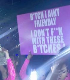 people holding up signs at a concert with lights in the background and one person raising their hands