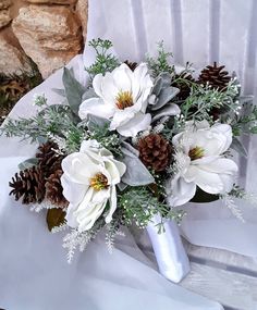 a bridal bouquet with white flowers and pine cones