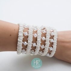 a woman's arm wearing white bracelets with crystal beads on the sides and a silver clasp