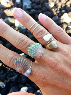 a woman's hand with rings and seashells on it