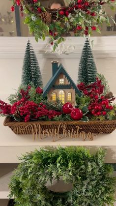 two christmas wreaths with red flowers and greenery in front of a house on the mantle