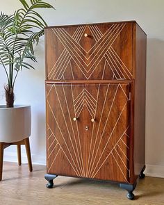 a wooden cabinet sitting next to a potted plant on top of a hard wood floor