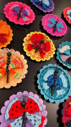 many colorful crocheted butterflies are arranged on a black surface with beads and bead