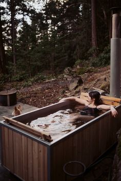 a woman laying in a hot tub surrounded by trees