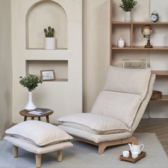 a chair and ottoman in a room with bookshelves, potted plants and pictures on the wall