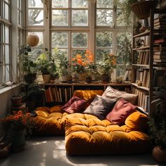 a living room filled with lots of plants and bookshelves in front of windows