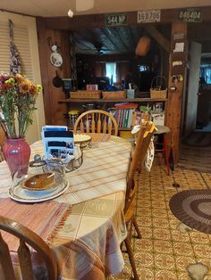 a dining room table with chairs and plates on it in front of a bookshelf