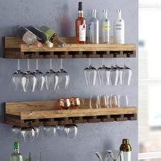 two wooden shelves with wine glasses and bottles on them, one holding several empty glasses