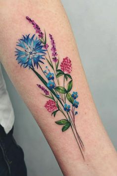 a colorful flower tattoo on the right arm and leg, with blue flowers growing out of it