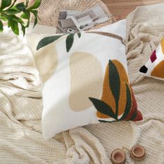 a pair of slippers are laying on a bed next to a pillow with an orange and green design