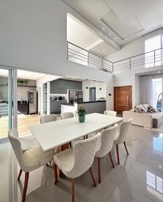 a dining room table with chairs and a vase on top of it in front of a large window