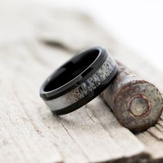 two wedding bands sitting next to each other on top of a piece of wood