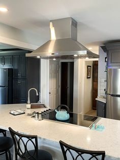 a kitchen with an island, stove and refrigerator in the middle of it is surrounded by black cabinets