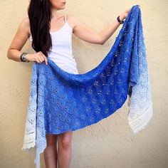 a woman is holding up a blue shawl