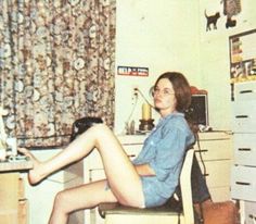 a woman sitting at a desk with her legs crossed in front of the computer monitor