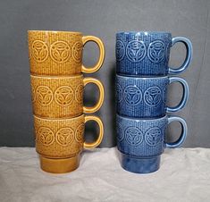 four blue and yellow coffee mugs sitting next to each other on top of a table