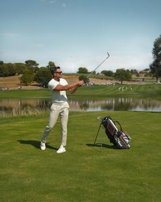 a man swinging a golf club on top of a green field