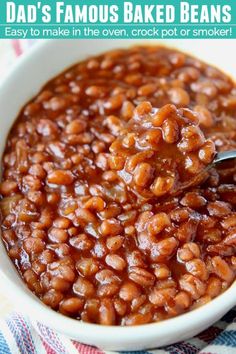 a spoon full of baked beans in a bowl with text overlay that reads dad's famous baked beans easy to make in the oven crock pot or smoker