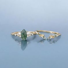 two gold rings with green and white stones on them, one has a pear shaped diamond in the middle