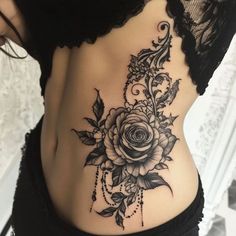 a woman's stomach with a rose tattoo on the side and black lace around it