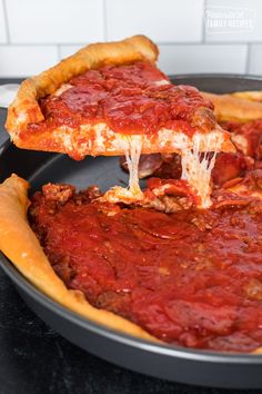 a deep dish pizza being lifted from a pan by a spatula with cheese and sauce on it