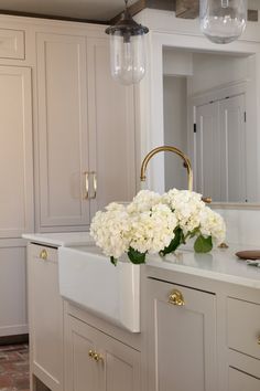 a kitchen with white cabinets and flowers on the counter