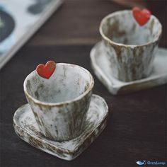 two cups and saucers with red hearts on them