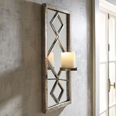 a candle is lit on the wall next to a mirror with an intricate design in it