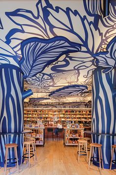 the interior of a library with blue and white striped walls, wooden stools, and bookshelves