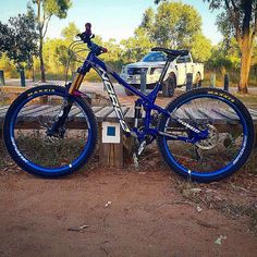 a blue and white mountain bike parked next to a parking meter in front of a truck