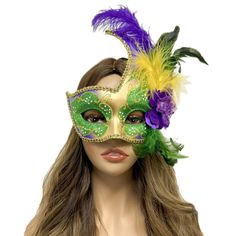 a woman wearing a green and purple mask with feathers on it's head,