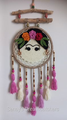 a decorative wall hanging with flowers and feathers on it's face, along with tassels