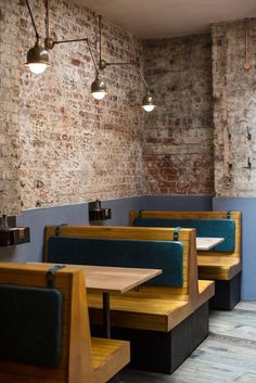 an empty restaurant with wooden booths and brick walls, along with blue upholstered benches