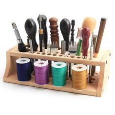 an assortment of sewing threads and spools in a wooden holder