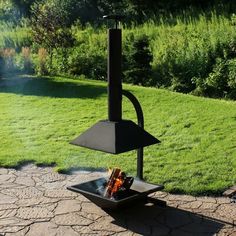 a fire pit sitting on top of a stone patio next to a lush green field