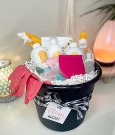 a bucket filled with lots of cleaning supplies on top of a counter next to a potted plant