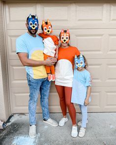 a man, woman and two children wearing animal masks in front of a garage door