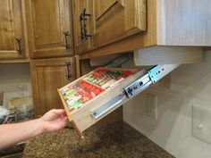 a person is holding a drawer open to pull out the contents from the kitchen cabinets