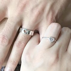 two people holding hands with rings on their fingers and one has a heart shaped diamond in the middle