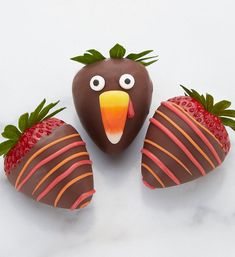 two chocolate covered strawberries with faces on them and one strawberry shaped like a turkey