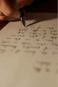 a person is writing on paper with a fountain pen and some type of cursive writing